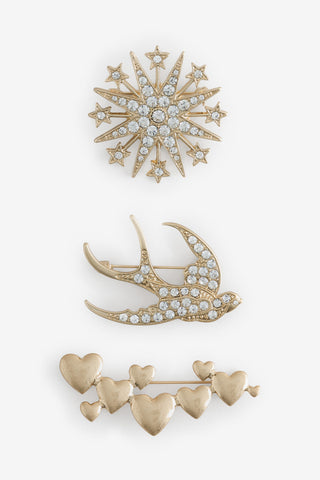 The Set of 3 Gold Brooches Pack shown flat against a white background - gold jewelled star, gold jewelled bird and gold heart cluster brooches. 