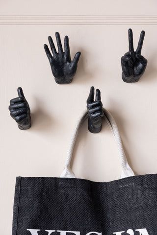 Four hand wall hooks on the wall, styled with a bag hanging from one of them.