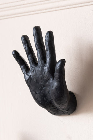 A hand wall hook on a plain wall.