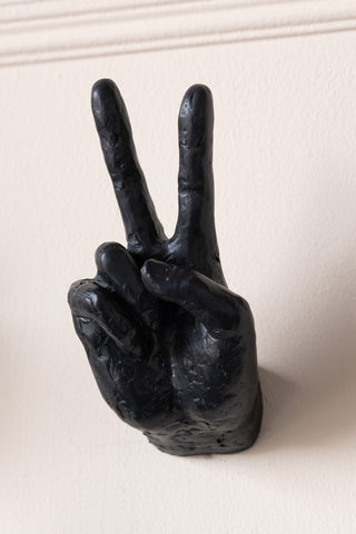 A peace sign hand wall hook displayed on a plain wall.