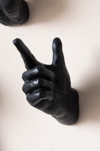 A pointing hand wall hook styled on a plain wall.
