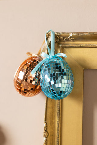 Two of the Set Of 6 Colourful Disco Easter Egg Decorations, styled hanging on the edge of a gold frame.
