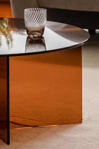 Close-up of the side of the Seventies Amber Glass Oval Coffee Table, displayed with a glass tumbler on.
