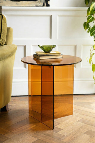  a trinket tray on top, next to a sofa and a plant.