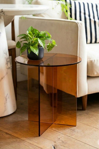 The Seventies Amber Glass Side Table with a plant on, displayed next to a sofa.