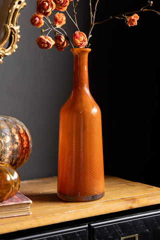 The Seventies Swirl Orange Glass Decanter shown styled as a vase with Ranunculus flowers. 