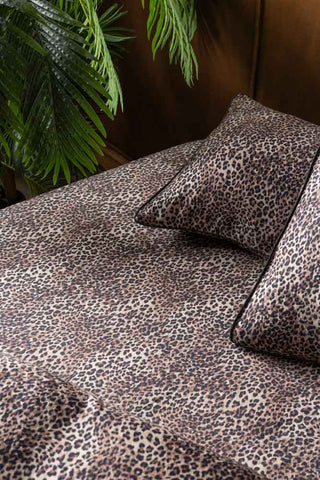 The Signature Leopard Print Cotton Sateen Fitted Sheet on a bed styled with some leopard print pillows and a plant.