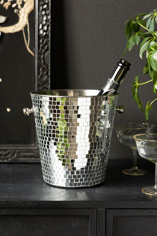 The Silver Disco Ball Ice Bucket shown on a black sideboard with a champagne bottle and champagne glasses. 