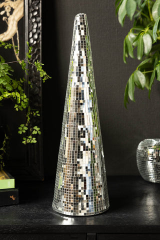The Silver Mirror Disco Christmas Cone shown on a black sideboard with plants and a disco ball in the background. 