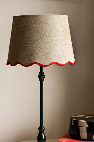 Lifestyle image of the Slim Table Lamp with Red Scalloped Linen Shade displayed on a marble table with other home accessories.