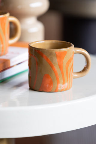 Lifestyle image of the Small Orange Abstract Marble Mug