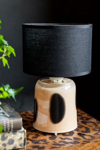 The Spotted Glass Rechargeable Table Lamp on a leopard print surface with some greenery and books.