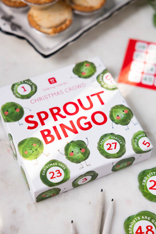 The Sprout Bingo Christmas Party Game box displayed on a white surface with some of the game pieces and a plate of mince pies.