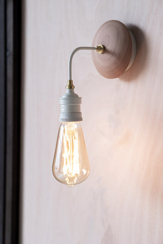 Lifestyle image of the Squirrel Cage E27 6W Clear LED Light Bulb on a wall lamp. 