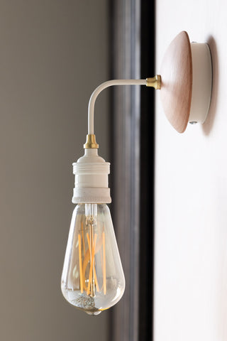 Lifestyle image of the Squirrel Cage E27 6W Clear LED Light Bulb on a wall lamp. 
