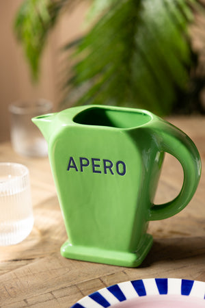 The Stylish Green Apero Water Jug styled on a table with a plate and some glasses.