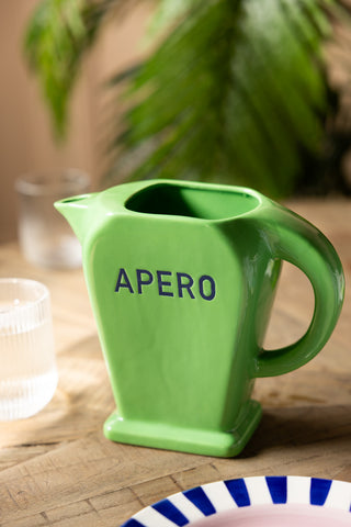 The Stylish Green Apero Water Jug styled on a table with a plate and some glasses.
