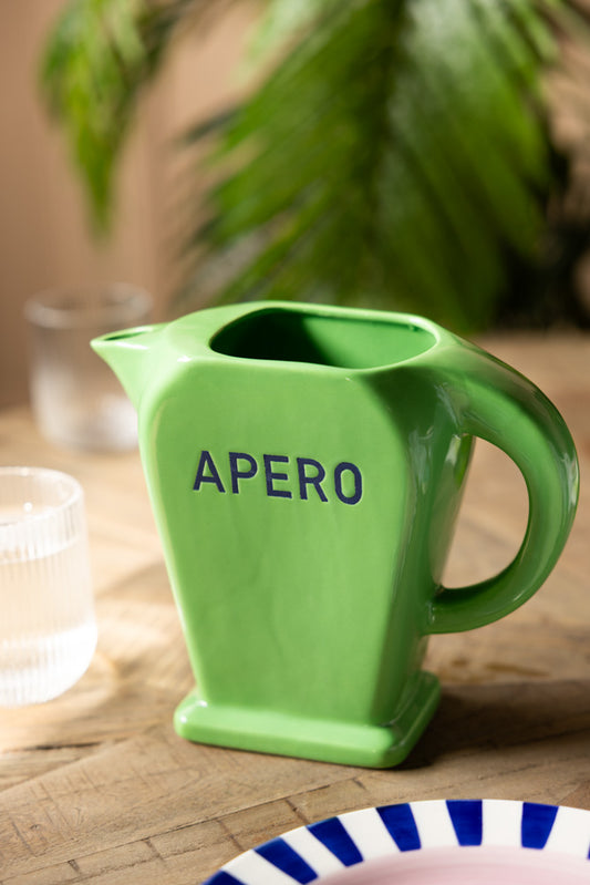 The Stylish Green Apero Water Jug styled on a table with a plate and some glasses.