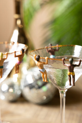 The Set of 6 Hunky Buddies Wine Glass Charms displayed on the edge of two cocktail glasses.