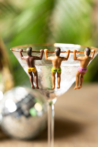 Three of the Set of 6 Hunky Buddies Wine Glass Charms on the edge of a cocktail glass.