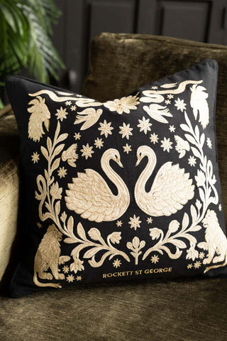 The Swan Tapestry Embroidered Cushion styled on a green sofa.