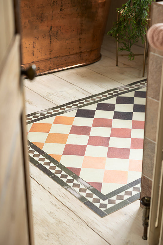 The Terracotta Checkered Durable Floor Mat, shown in a bathroom against a copper bath tub.