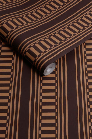 The roll of The Curiosity Shop Stripe Wallpaper in Aubergine
