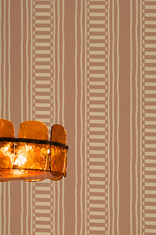 The Curiosity Shop Stripe Wallpaper in Blush shown in detail with an amber glass ceiling light at the side of the image. 