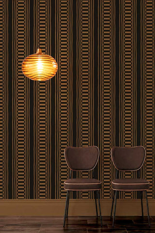 The Curiosity Shop Stripe Wallpaper in Noir shown with chocolate brown chairs in front of the wallpaper and an amber glass light. 