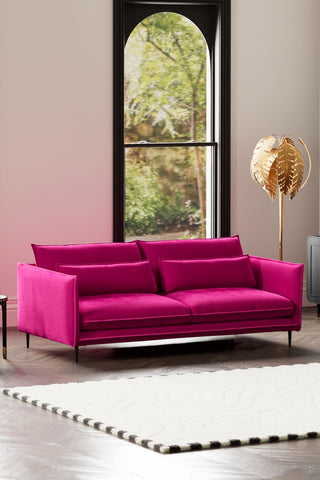 The Lola 4 Seater Sofa in Harry's Pink Velvet styled with a rug, floor lamp and side table in front of a window.