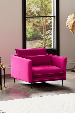 The Lola Snuggle Seat in Harry's Pink Velvet styled with a rug, floor lamp and side table in front of a window.