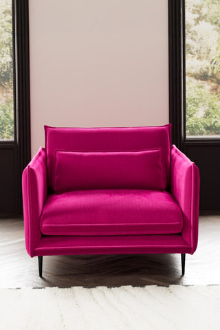 The Lola Snuggle Seat in Harry's Pink Velvet styled with a rug in front of two windows.