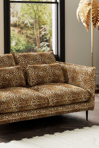 Close-up of one side of The Lola 2 Seater Sofa in Leopard Print Velvet styled with a rug and floor lamp.