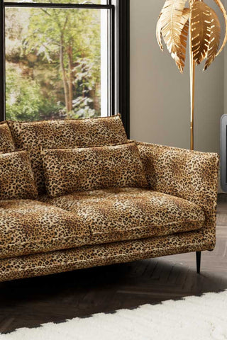 Close-up of one side of The Lola 3 Seater Sofa in Leopard Print Velvet, styled with a rug and floor lamp.