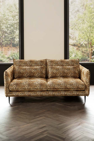 The Lola 3 Seater Sofa in Leopard Print Velvet styled in front of two windows.