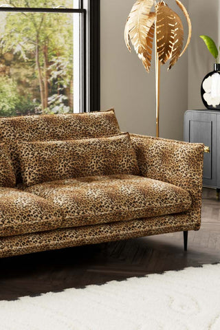 Close-up of one side of The Lola 4 Seater Sofa in Leopard Print Velvet, styled with a rug, floor lamp, sideboard and vase.
