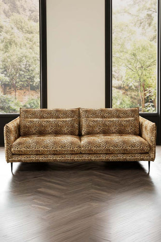 The Lola 4 Seater Sofa in Leopard Print Velvet styled in front of two windows.