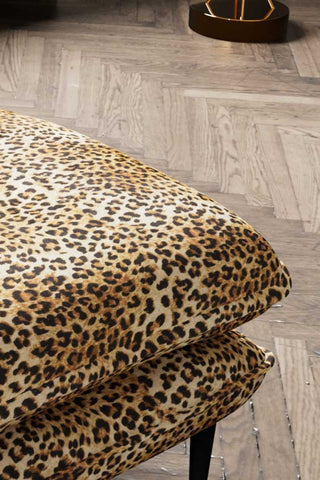 Close-up of the The Lola Footstool in Leopard Print Velvet displayed on a wooden floor.