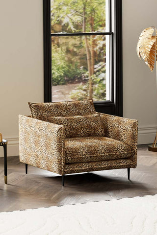 The Lola Snuggle Seat in Leopard Print Velvet styled with a rug, floor lamp and side table in front of a window.