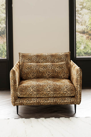 The Lola Snuggle Seat in Leopard Print Velvet styled with a rug in front of two windows.