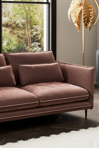 Close-up of one side of The Lola 3 Seater Sofa in Luxe Pink Velvet, with a floor lamp and window in the background.