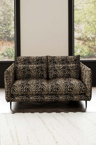 The Lola 2 Seater Sofa in Tiger Print Velvet styled with a rug in front of two windows.