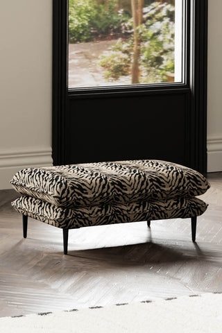 The Lola Footstool in Tiger Print Velvet styled next to a rug with a window in the background.