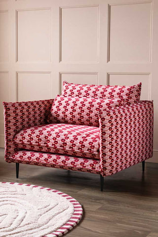 The Lola Snuggle Seat in Woven Red & Pink Lips Velvet styled with a rug in front of a panelled wall.