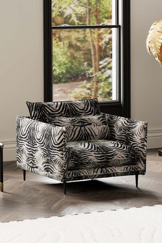 The Lola Snuggle Seat in Zebra Print Velvet styled with a rug in front of a window.
