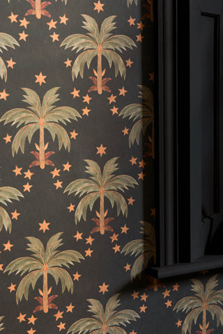 A close up of The Midnight Palms Wallpaper in Noir against black shutters.