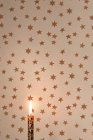 A close up of The Midnight Skies Wallpaper in Ivory with a candle. 