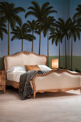The Palm Paradiso Mural Wallpaper in Coast shown in a bedroom with a French-style bed. 