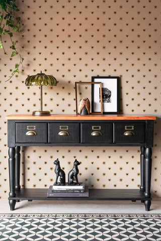 The Sacred Hearts Wallpaper in Ivory Noir shown in a hallway setting with a black wood console table. 