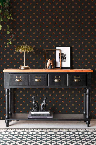 The Sacred Hearts Wallpaper in Noir Red shown in a hallway with a black wooden console table. 
